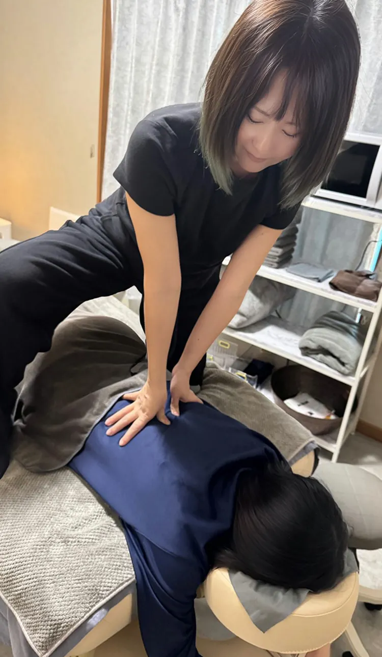 女性セラピストが女性のふくらはぎをマッサージしている